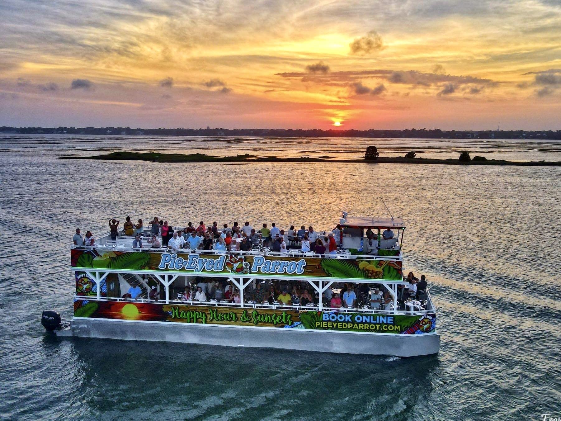 A boat full of people on the water at sunset.