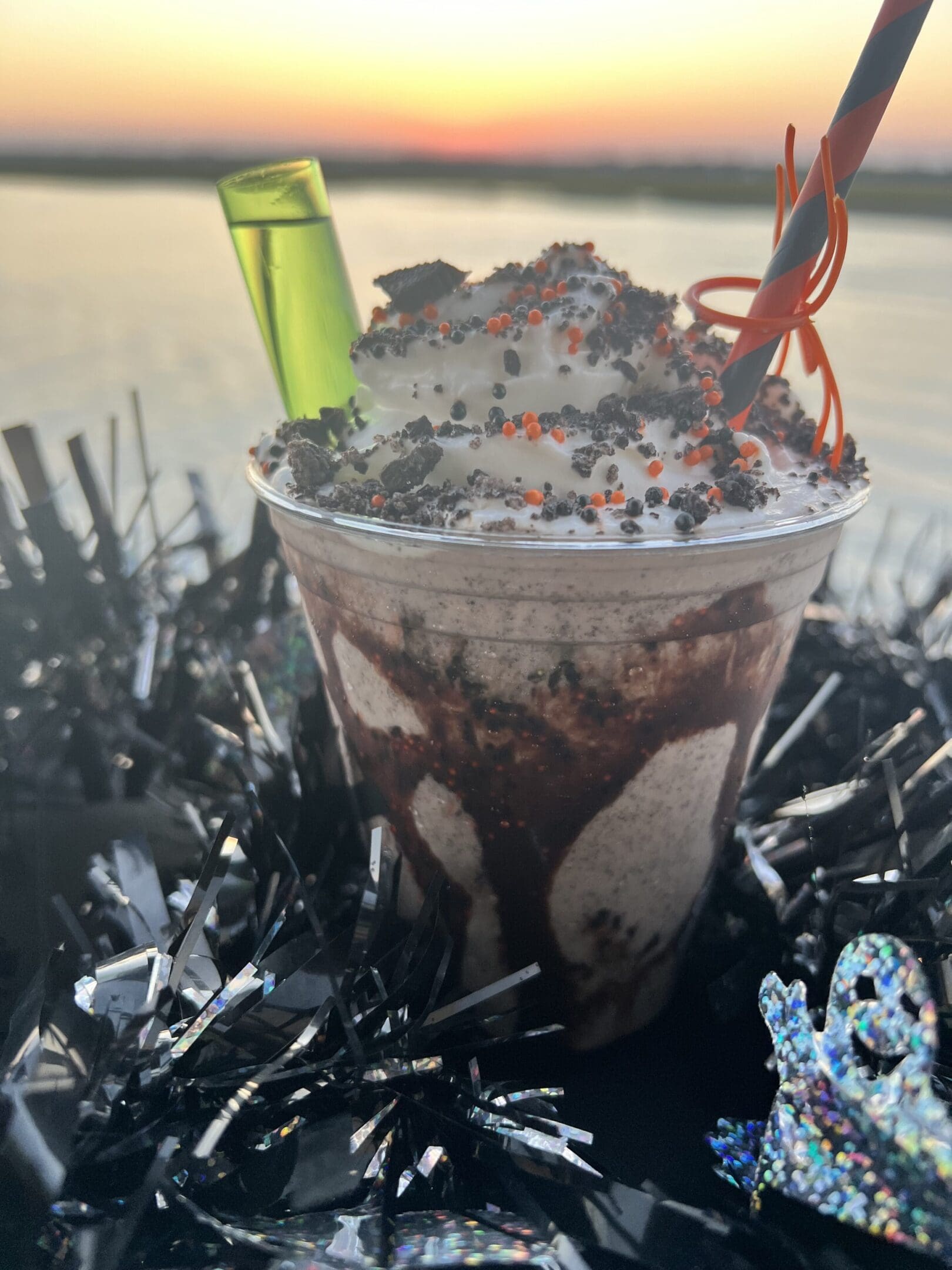 A cup of chocolate ice cream with a straw.