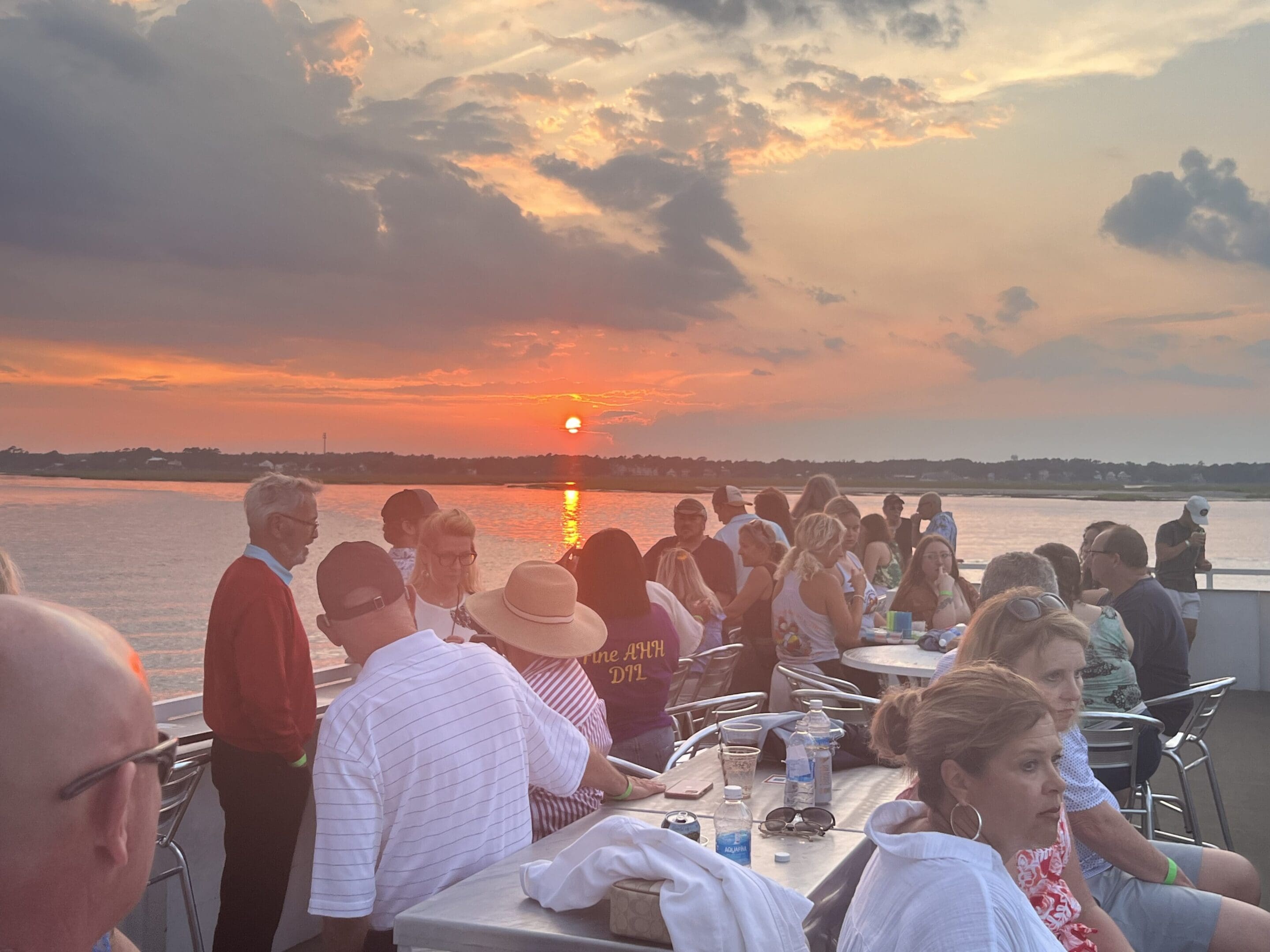 A group of people sitting at tables on the water.